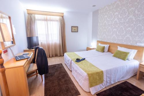 a bedroom with a bed and a desk and a television at Hotel Eurosol Alcanena in Alcanena