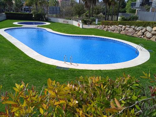 - une grande piscine dans une cour avec gazon dans l'établissement Port Aventura 5 min à pied - Superbe appartement, à Salou