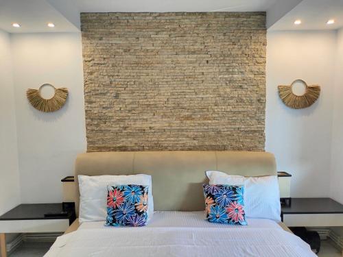 a bedroom with a bed with two pillows and a brick wall at City Park Apartment in Constanţa