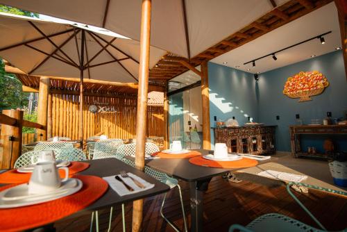 ein Restaurant mit Tischen, Stühlen und einem Sonnenschirm in der Unterkunft Pousada Xica in Fernando de Noronha