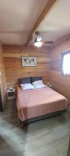 ein Schlafzimmer mit einem Bett in einem Holzzimmer in der Unterkunft Bungalow de Coco in Saint-Paul