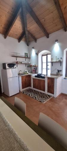 a large kitchen with wooden cabinets and a white refrigerator at Holiday Villa Old Qeparo in Qeparo