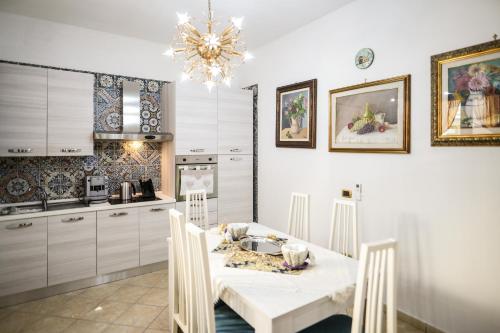 una cucina con tavolo bianco, sedie e lampadario pendente di Zeus a San Giorgio Ionico