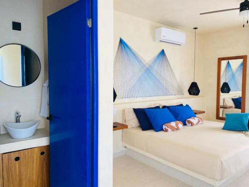 a bedroom with a bed with blue pillows and a sink at Sunsteps suite pyramids in Holbox Island