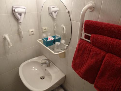 La salle de bains est pourvue d'un lavabo, d'un miroir et de serviettes rouges. dans l'établissement La Vieille Tour, à Salavas