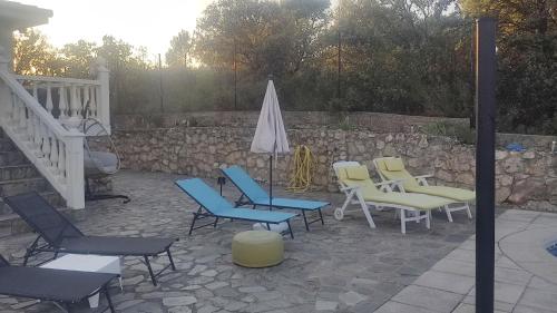 a group of chairs and an umbrella on a patio at Increíble Casa Rural en la Sierra de Altomira Piscina privada y Barbacoa in Albalate de Zorita
