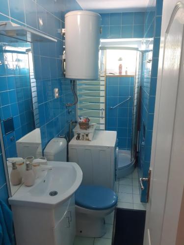 a blue tiled bathroom with a toilet and a sink at Apartman LEON in Livno