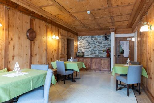 Sport Hotel Stella Alpina في كوغولو: غرفة طعام بها طاولات خضراء وكراسي وجدران خشبية