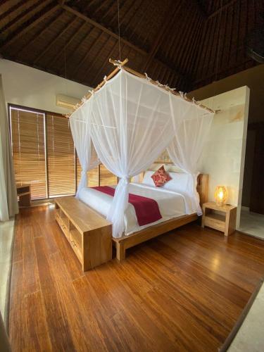 a bedroom with a bed with a mosquito net at Villa DiKebun in Uluwatu
