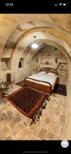 a bedroom with a bed in a stone room at Monastery cave Hotel Cappadocia in Mustafapaşa