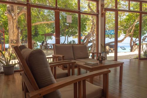 a living room with chairs and a table and windows at Thundi Village & Spa in Maalhos