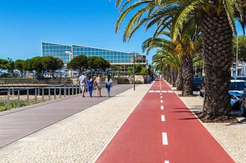 a red sidewalk with palm trees and people walking on it at Avenida House a 700 metros da praia in Esposende
