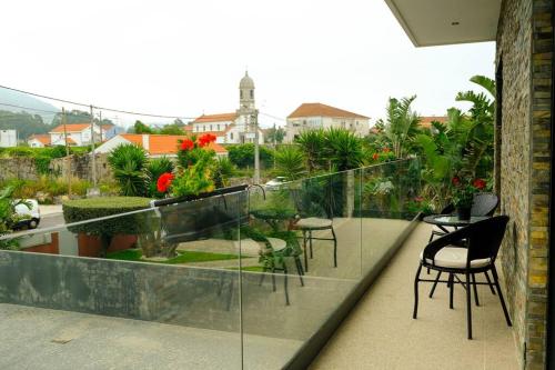a balcony with chairs and tables and a garden at Avenida House a 700 metros da praia in Esposende