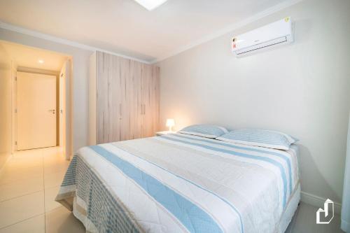 1 dormitorio con 1 cama con manta azul y blanca en Kremer Residence - Apartamento 302: Com todos os ambientes climatizados, en Bombinhas