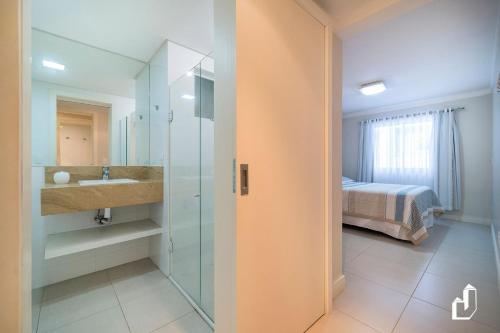 1 cama y baño con lavabo y ducha. en Kremer Residence - Apartamento 302: Com todos os ambientes climatizados, en Bombinhas
