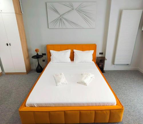 uma grande cama laranja com duas almofadas brancas em The Palm Studio em Mamaia