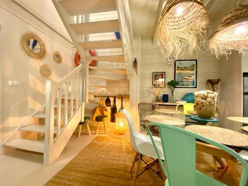 ein Wohnzimmer mit einer Treppe, einem Tisch und Stühlen in der Unterkunft La Maison Bleue in Cap-Ferret
