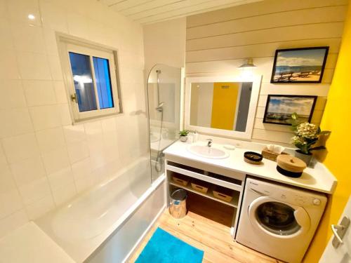 a bathroom with a sink and a washing machine at La Maison Bleue in Cap-Ferret