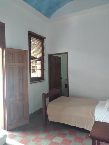 a bedroom with a bed and a window and a door at Hotel Colonial Victonella in Granada