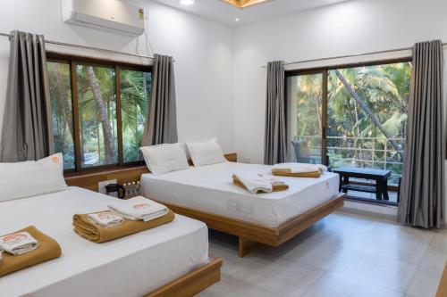 two beds in a room with a view of the jungle at Coco Palms Inn in Alibaug