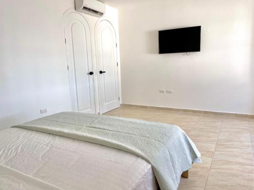 a white bedroom with a bed and a flat screen tv at Beautiful 2 bedroom, pool, beach in Manta