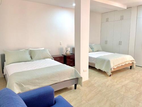 1 dormitorio con 2 camas y silla azul en Hermoso Departamento en Lomas de Barbasquillo, en Manta