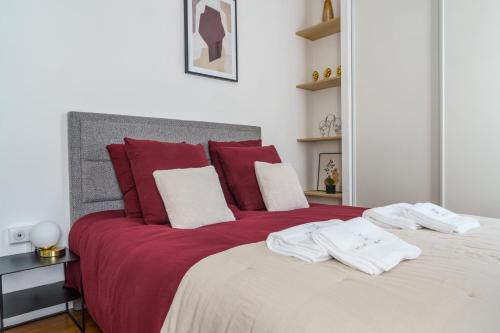 una camera da letto con un grande letto con cuscini rossi e bianchi di Le Balcon des Arts - PrestiPlace Tours a Tours