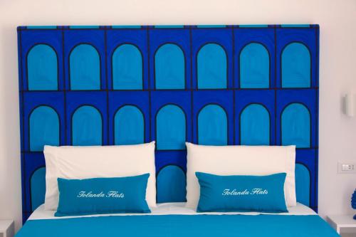a blue headboard with two blue pillows on a bed at Iolanda flats in Piano di Sorrento