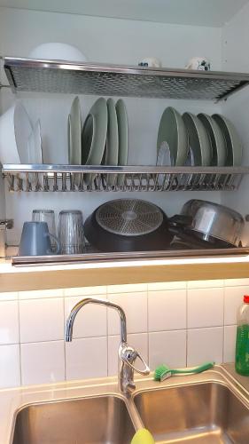 a kitchen with a sink and a shelf with dishes at Cozy Aparti in Vantaa