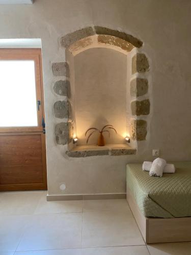 a bedroom with a stone wall with a bed and a window at Avli House Vori in Vóroi