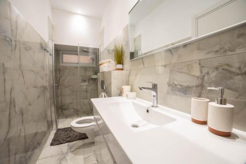 a white bathroom with a sink and a toilet at Luxury units by Hilton beach in Tel Aviv