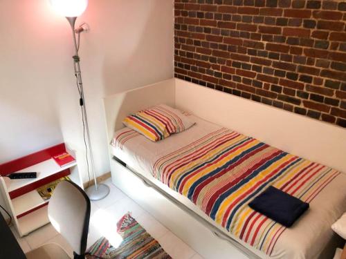 a small bedroom with a bed with a brick wall at Gîte au cœur d'une résidence d'artiste in Saint-Aubin-de-Bonneval