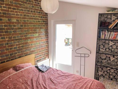 a bedroom with a brick wall and a pink bed at Gîte au cœur d'une résidence d'artiste in Saint-Aubin-de-Bonneval