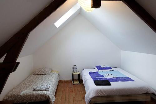 a attic bedroom with a bed and a chair at Gîte au cœur d'une résidence d'artiste in Saint-Aubin-de-Bonneval