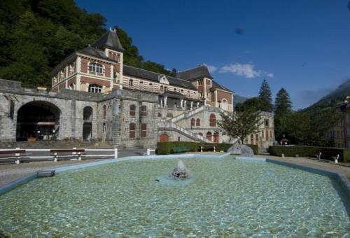 un grand bâtiment avec une fontaine devant lui dans l'établissement Appartement douillet eaux bonnes/vallée d’ossau, à Eaux-Bonnes