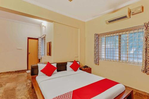 a bedroom with a large white bed with red pillows at Goyal Residency in Bangalore