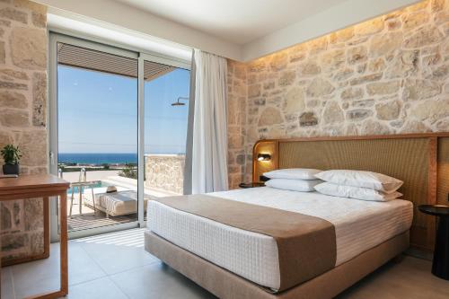 a bedroom with a bed and a large window at Petras Resort in Falasarna