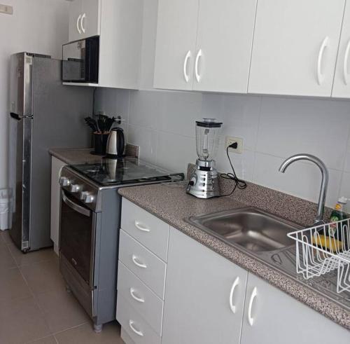 uma cozinha com lavatório, fogão e frigorífico em Precioso departamento equipado - Cochera incluida em Chila Pampa