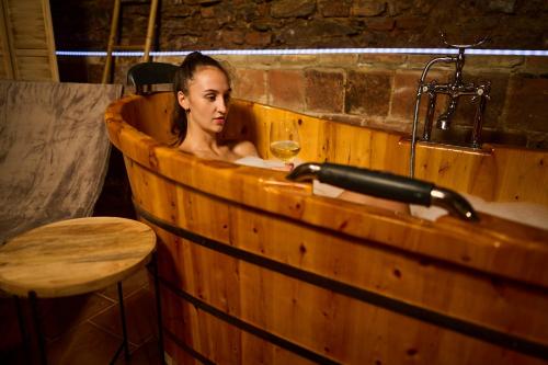 a woman sitting in a wooden tub with a glass of wine at Sklep jinak in Znojmo