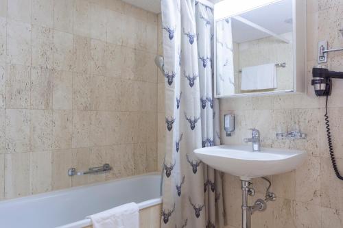 ein Badezimmer mit einem Waschbecken, einer Badewanne und einem Spiegel in der Unterkunft Appartments Cervus in St. Moritz