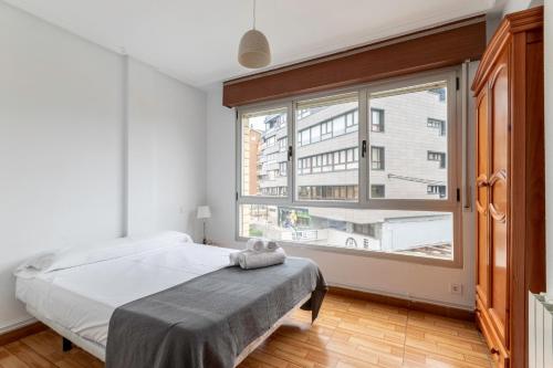- une chambre avec un lit et une grande fenêtre dans l'établissement La Arena Apartamentos Zierbena, à La Arena