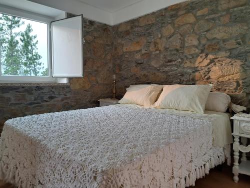 a bedroom with a bed and a stone wall at A Casa dos Avós - Alojamento Local in Sertã