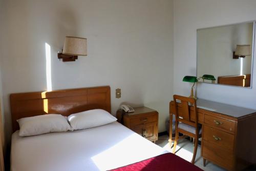 1 dormitorio con cama, escritorio y espejo en Hotel Calvete en Torreón