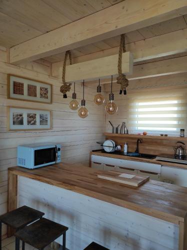 a kitchen with wooden walls and a counter with a microwave at Jotwingia - Domki z Widokiem in Stare Juchy