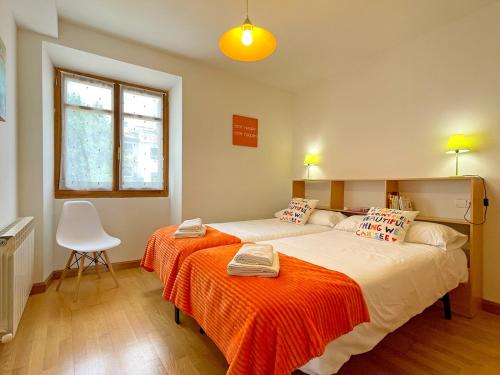 sypialnia z dużym łóżkiem i pomarańczowym kocem w obiekcie Apartamentos Puente La Reina w mieście Puente la Reina
