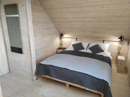ein Schlafzimmer mit einem Bett in einer Holzwand in der Unterkunft Jotwingia - Domki z Widokiem in Stare Juchy