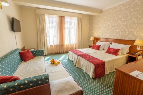 une chambre d'hôtel avec deux lits et un canapé dans l'établissement Eurosol Gouveia, à Gouveia