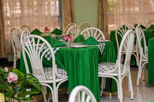 uma mesa com uma toalha de mesa verde e cadeiras brancas em GLAMOUR APOLLO HOTEL em Webuye