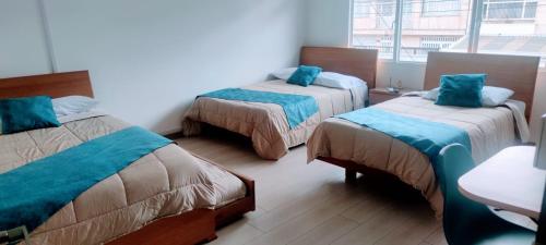 a room with two beds with blue pillows at CASA HOTEL NUESTRA TIERRA EMBAJADA CORFERIAS AEROPUERTO y otros in Bogotá