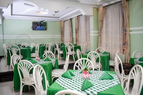 uma sala de jantar com mesas verdes e cadeiras brancas em GLAMOUR APOLLO HOTEL em Webuye